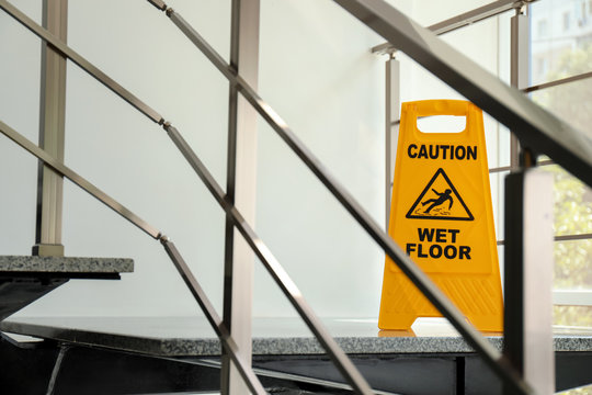 Safety sign with phrase Caution wet floor on stairs. Cleaning service