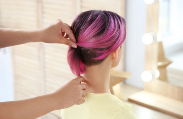 Professional hairdresser working with young woman in beauty salon. Trendy hair color