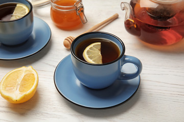 Cup with black tea and lemon on table