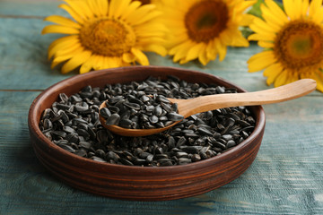 Bowl and spoon with sunflower seeds on table, closeup