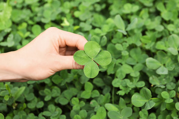 Woman holding four-leaf clover outdoors, closeup © New Africa