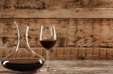 Elegant decanter and glass with red wine on wooden table