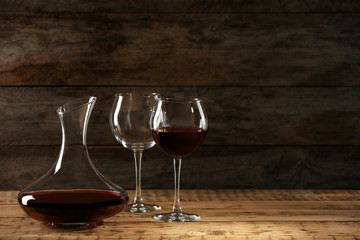 Elegant decanter with red wine and glasses on wooden table
