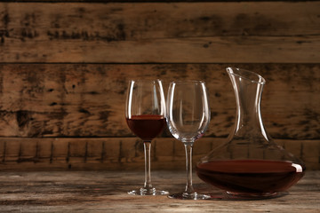 Elegant decanter with red wine and glasses on wooden table