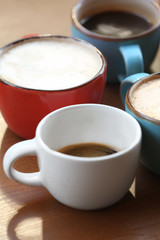 Cups of fresh aromatic coffee on wooden table, closeup