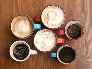 Cups of fresh aromatic coffee on wooden table, top view