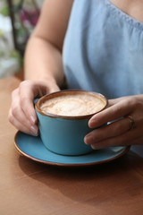 Woman with cup of fresh aromatic coffee at table, closeup