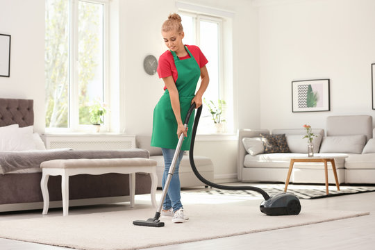 Woman removing dirt from carpet with vacuum cleaner indoors