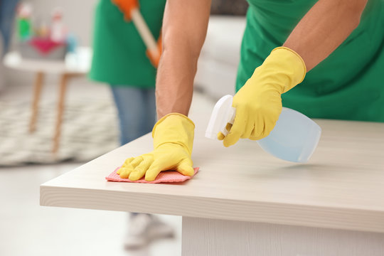 Man in gloves cleaning table indoors, closeup