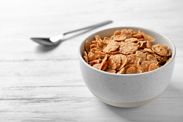 Bowl with cornflakes on light table. Whole grain cereal for breakfast