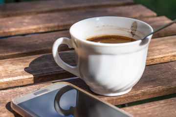 White cup of black coffee and smartphone
