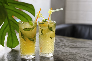 Glasses of iced lemonade on table indoors
