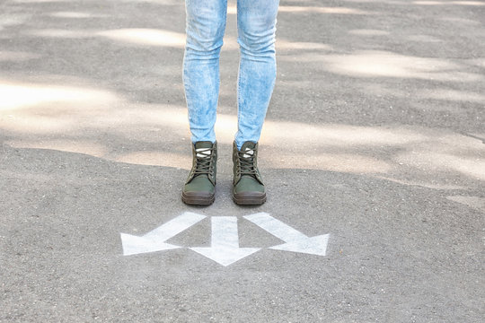 Woman standing near arrows on asphalt. Choice concept