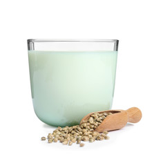Scoop with hemp seeds and glass of milk on white background