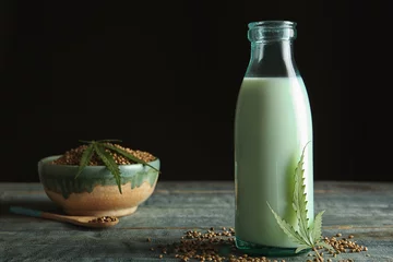 Wandaufkleber Bottle of hemp milk on wooden table © New Africa