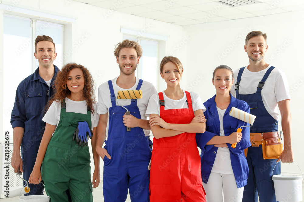 Poster team of professional painters with tools indoors