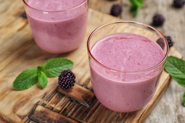 Glasses with blackberry yogurt smoothies on wooden board