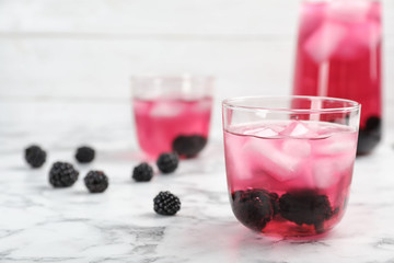 Glass with iced blackberry lemonade on marble table