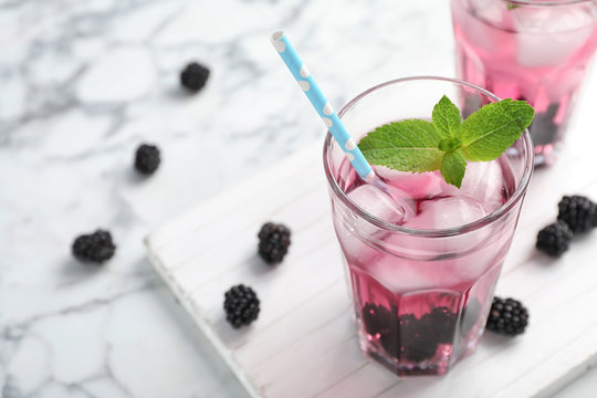 Glass with iced blackberry lemonade on marble table
