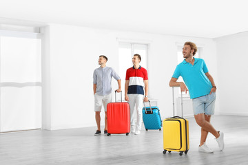 Group of young people with suitcases in light room