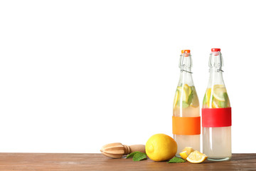 Bottles with natural lemonade on table against white background