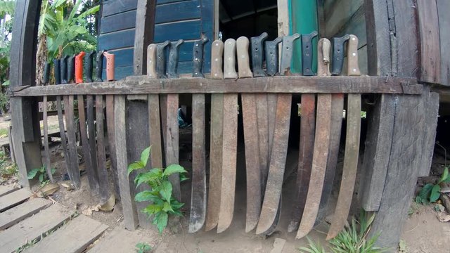 Lots of machetes outside a lode at amazon rain forest jungle. Puerto Maldonado Peru. day time camera moving past and filming knives.