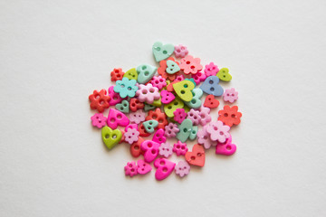 Mixed coloured bright buttons. Colored buttons in the shape of heart. Button plastic colorful on white background and copy space. Beautiful color buttons. Sewing buttons.  Many color plastic.