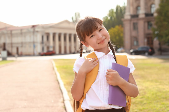 Little girl with backpack and notebook outdoors. Stationery for school