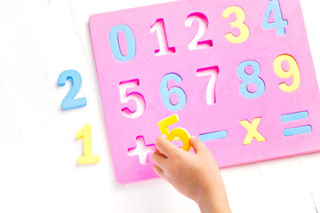 The child is studying the numbers and the account. Arranges the colored blocks to the desired numbers. Mathematics for children.