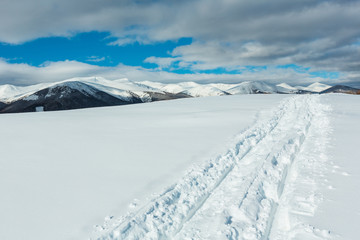 Sledge trace and footprints on winter mountain hill top