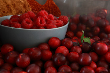 Raspberries and plums on a black table. Berries and fruit. 