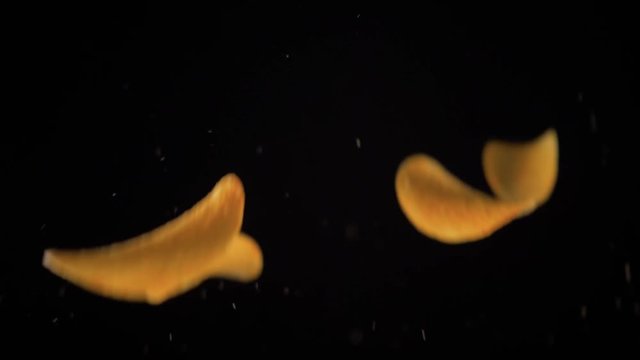 potato chips in free fall on a black background. Slow motion. The view from the side. Pringles