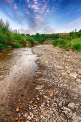 Fototapeta na wymiar Mountain river stream of water in the rocks with majestic blue sky.