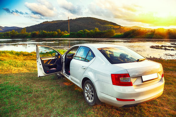 White car in beautiful mountains with scenic view  at sunset time near river