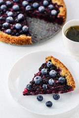 Slice of pie with black currant and blueberries and a cup of tea