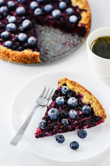 Slice of pie with black currant and blueberries and a cup of tea