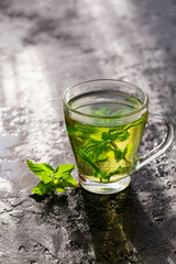 Cup of mint tea on table, dark background