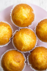 Cupcakes on a pink plate over white wooden surface, overhead view. Closeup.