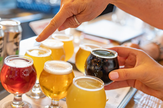 Female Hand Picking Up Glass of Micro Brew Beer From Variety on Tray