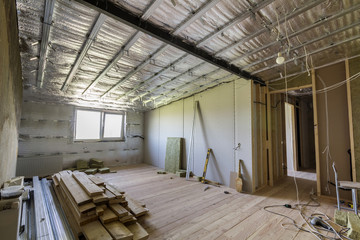 Room under construction with silver aluminum insulation foil and drywall on walls and ceiling.