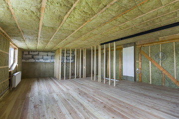 Construction and renovation of big spacious empty unfinished attic room with oak floor, walls and...