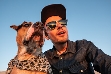 Spoiled self portrait concept: man trying to make a selfie with his funny dog. Young male person...