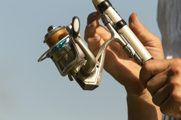 Naklejka premium Fisherman with a fishing rod on the river bank. A fisherman is fishing. Fish, rotating coil. - The concept of rural recreation. Article about fishing.