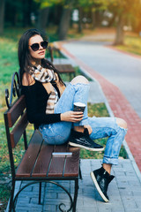 stylish girl with glasses resting in the Park, fashionable girl drinking coffee