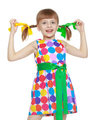 Fototapeta na wymiar A little girl in a dress with a pattern from multi-colored circl