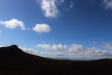 Fototapeta na wymiar Mountain top against blue sky with fluffy white clouds