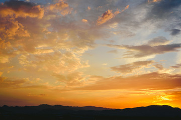 Fototapeta na wymiar Beautiful sunset with the sun of orange tones behind the mountains and deep blue sky