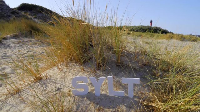Sylt D&uuml;nen Landschaft mit Strandhafer  mit Sylt Buchstaben Leuchtturm H&ouml;rnum im Hintergrund