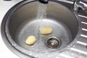 Peeled fresh potatoes in the kitchen sink