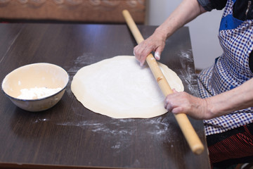 Senior woman hands knead dough on a table in her home kitchen